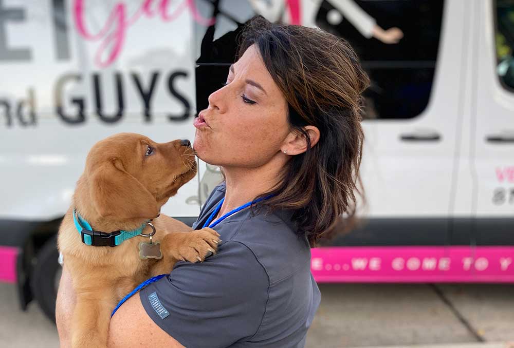 A veterinary technician getting kisses from a patient