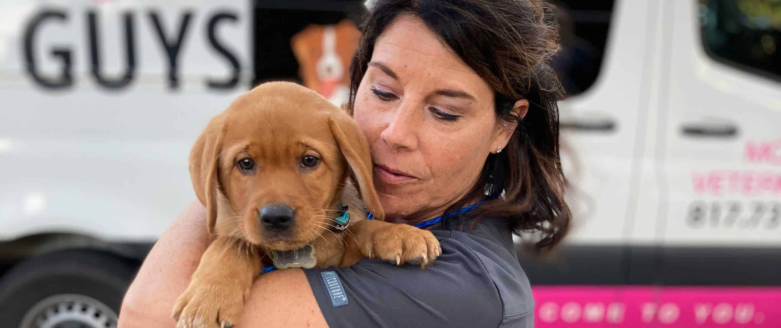 A veterinary technician holding a puppy outside our van